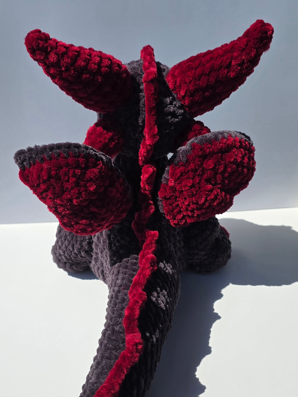 Peluche de dragón sentado con ojos brillantes de colores