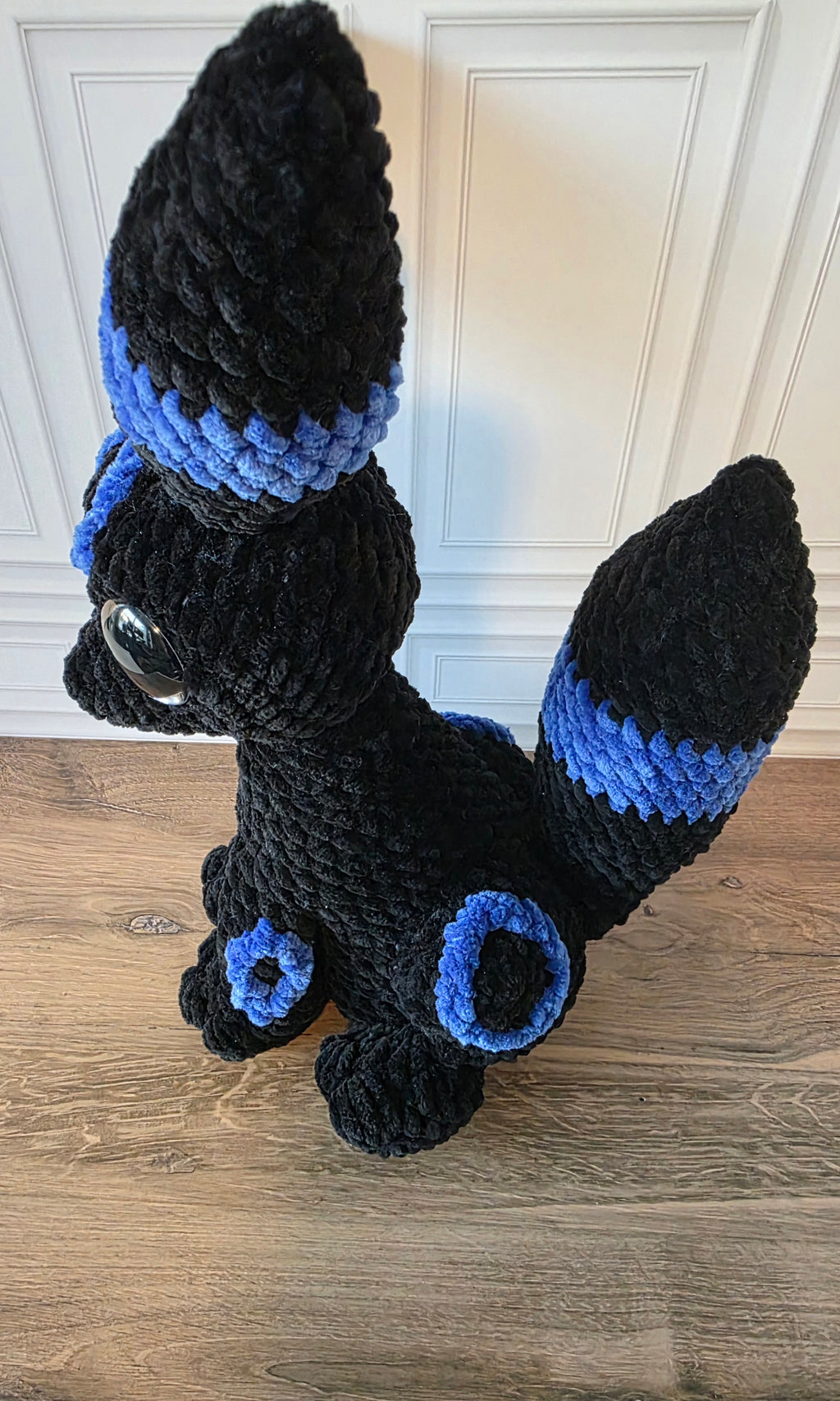 Peluche de dragón sentado con ojos brillantes de colores