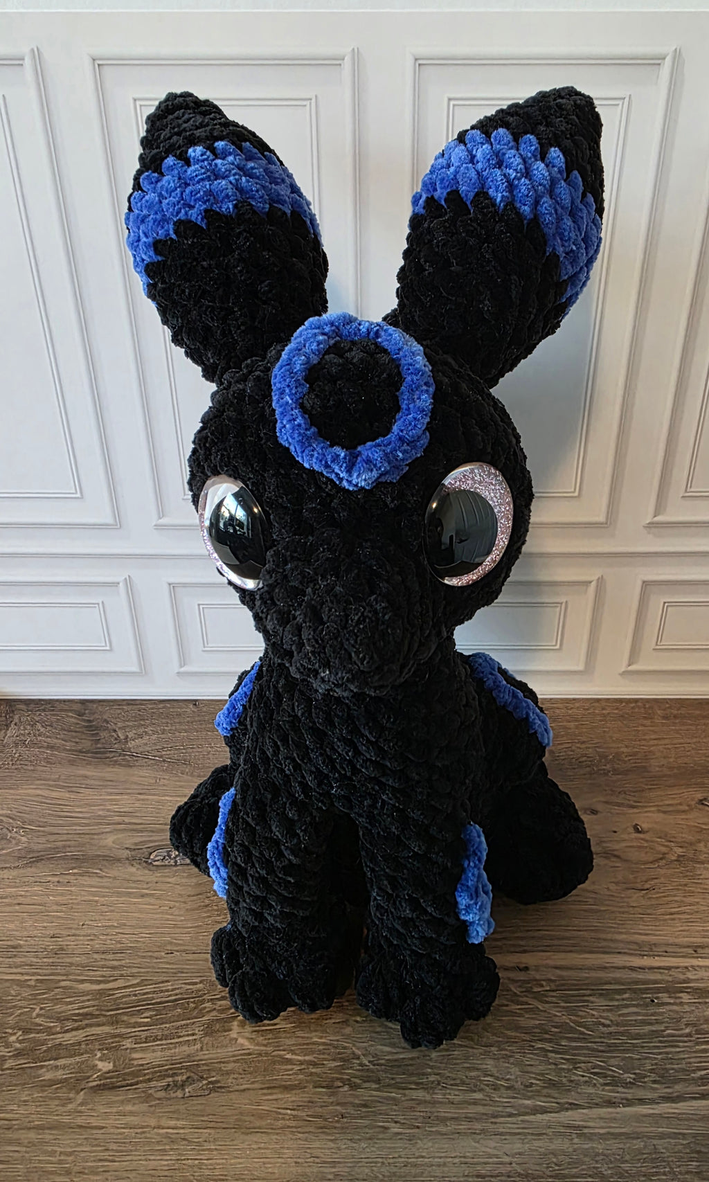 Peluche de dragón sentado con ojos brillantes de colores