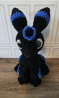 Peluche de dragón sentado con ojos brillantes de colores
